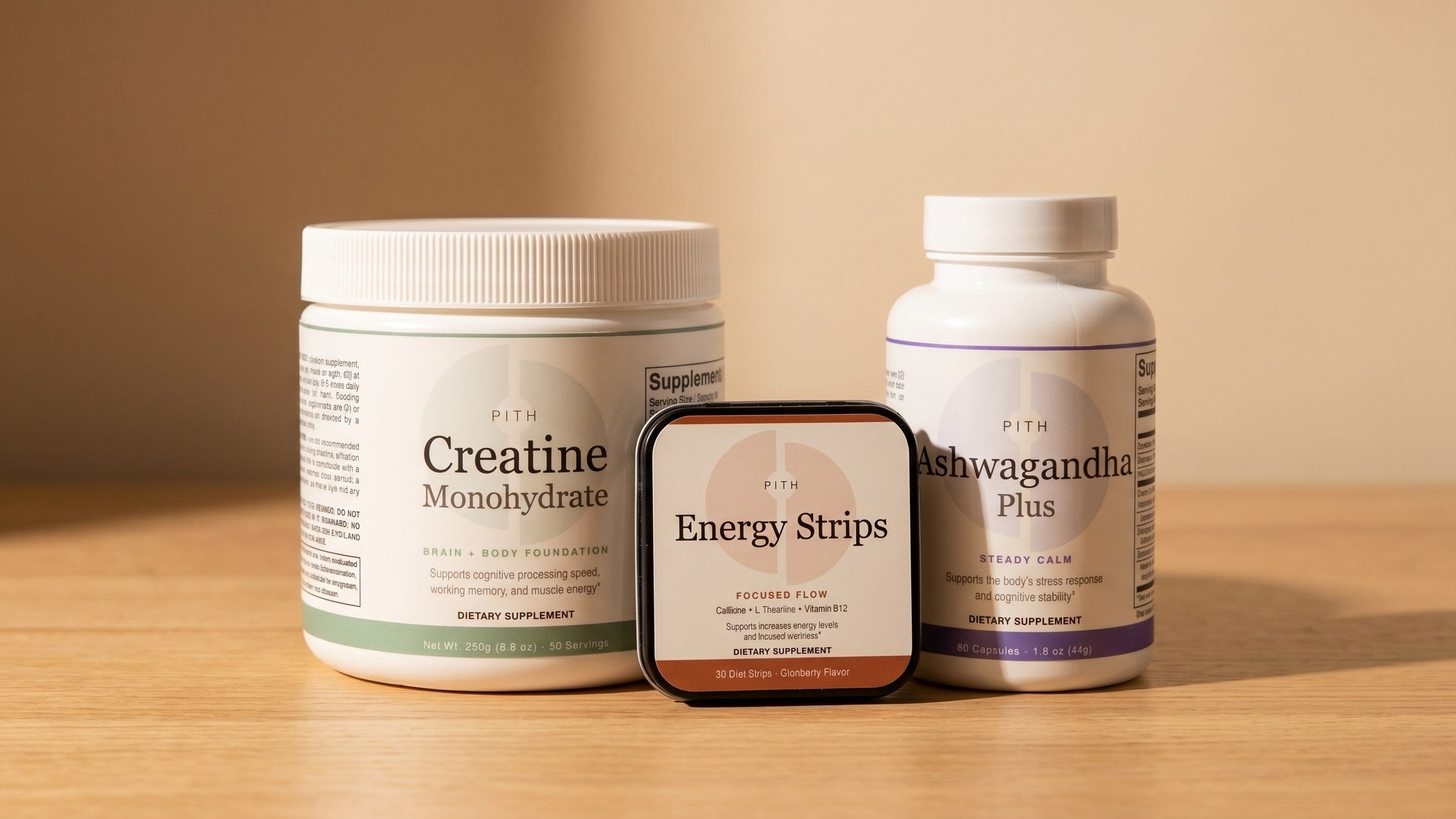 The full Pith supplement set — creatine jar, energy strips tin, and ashwagandha bottle — grouped together on a warm surface